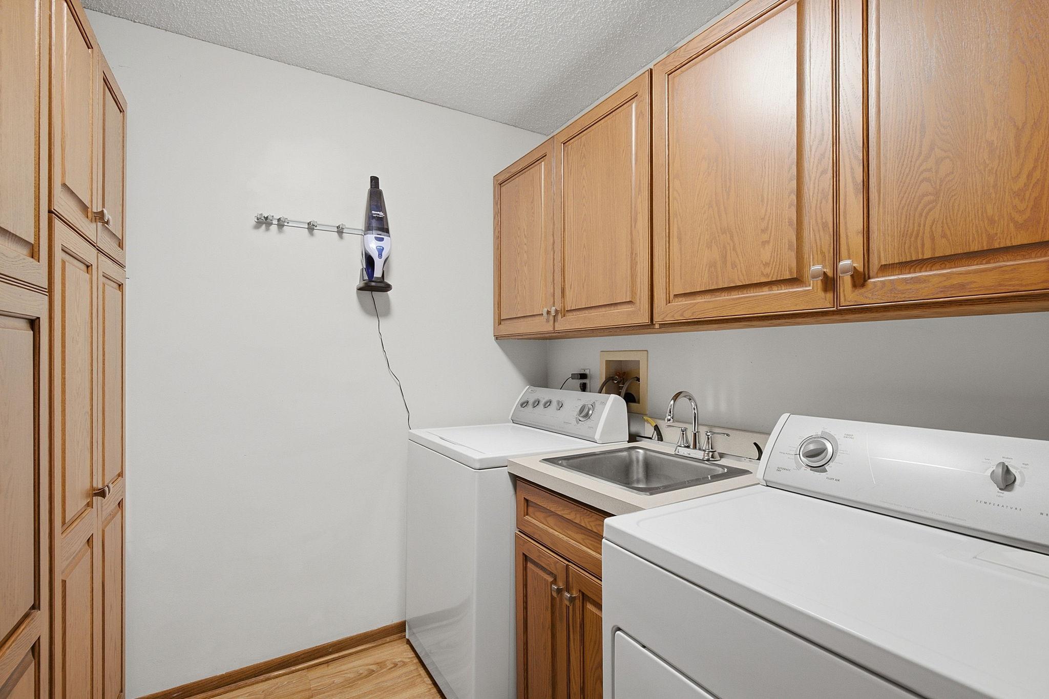 In-Unit Laundry - Dedicated laundry room includes washer and dryer, utility sink, extensive cabinetry, and additional storage for everyday household needs.