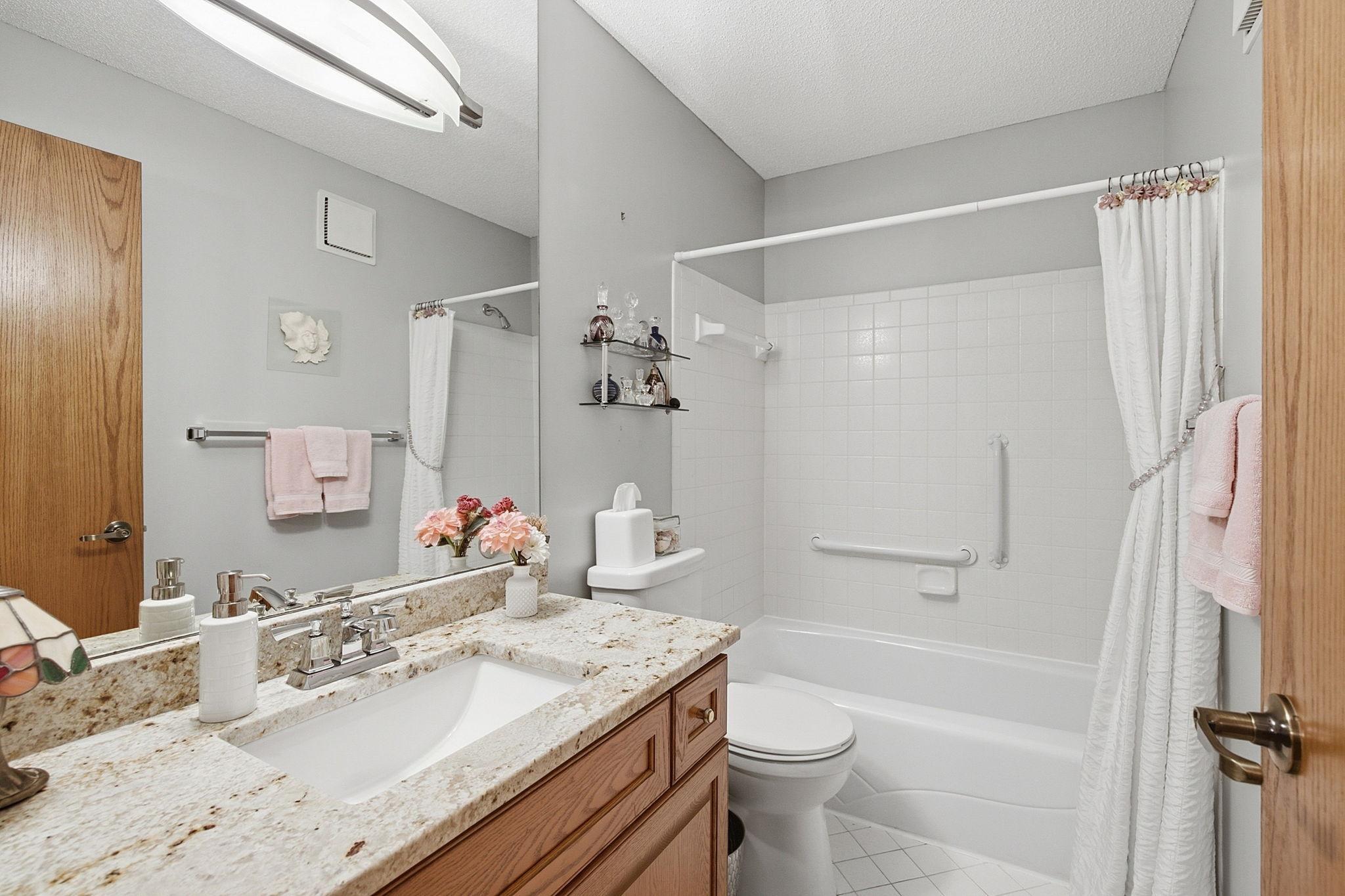 Full Bathroom - Bright full bath features a granite-topped vanity, tub/shower combination, tile flooring, large mirror, and grab bars for added convenience.