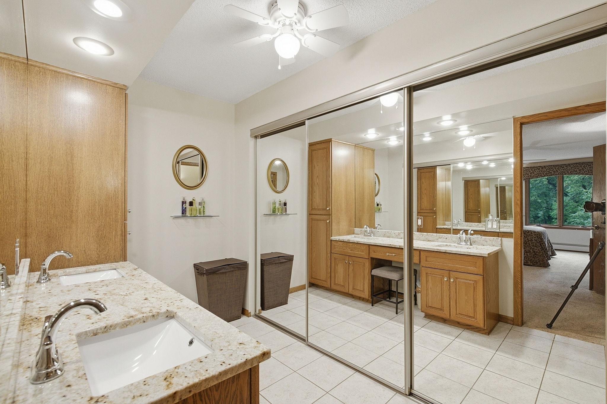 Dressing Area - Spacious dressing and vanity area features a granite countertop, extensive cabinetry, tile flooring, recessed lighting, and large mirrored closet doors.
