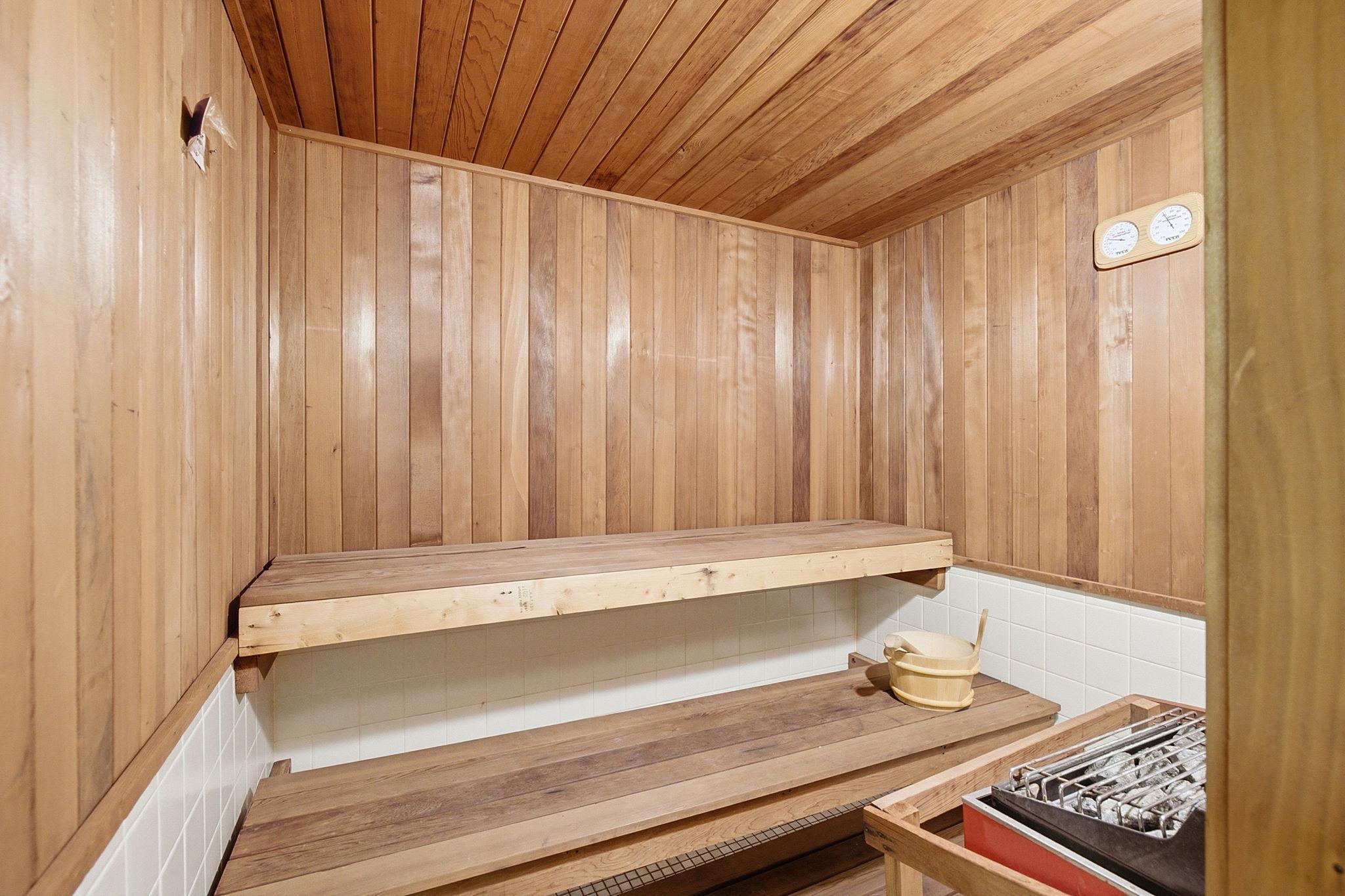 Sauna - Wood-paneled community sauna with tiered bench seating, conveniently located near the pool and locker room.