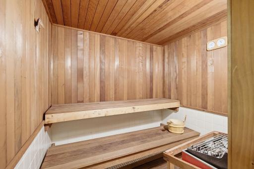 Sauna - Wood-paneled community sauna with tiered bench seating, conveniently located near the pool and locker room.