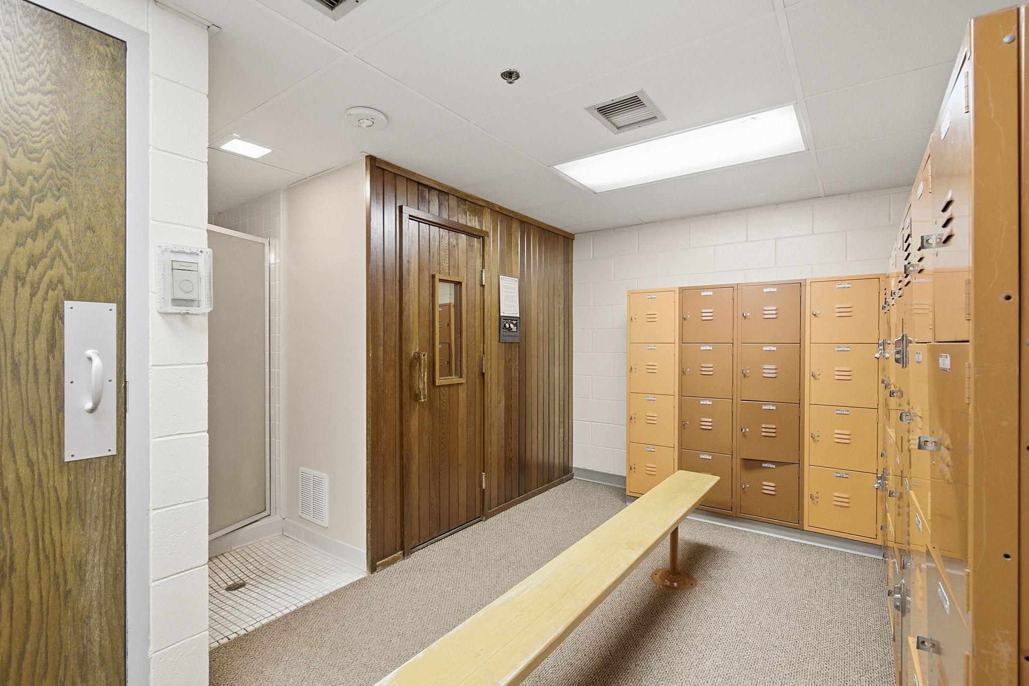 Locker Room - Community locker room with individual lockers, bench seating, shower area, and direct access to the pool and sauna facilities.