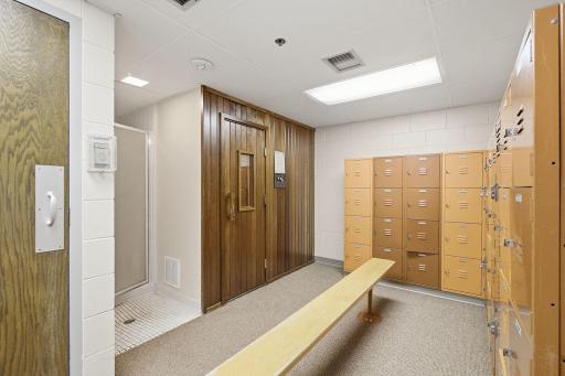 Locker Room - Community locker room with individual lockers, bench seating, shower area, and direct access to the pool and sauna facilities.