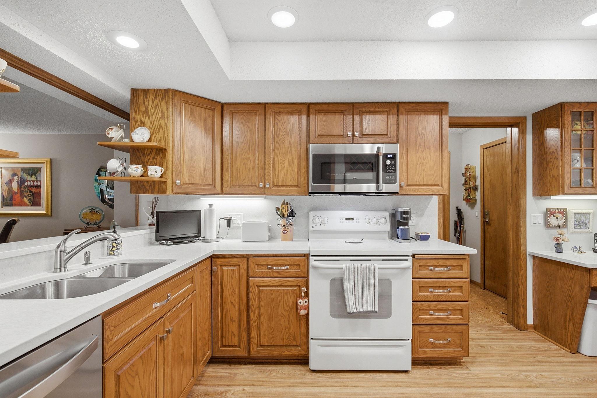 Updated Kitchen - Newer quartz countertops complement the warm oak cabinetry, with abundant workspace, generous storage, and a convenient pass-through to the living area.