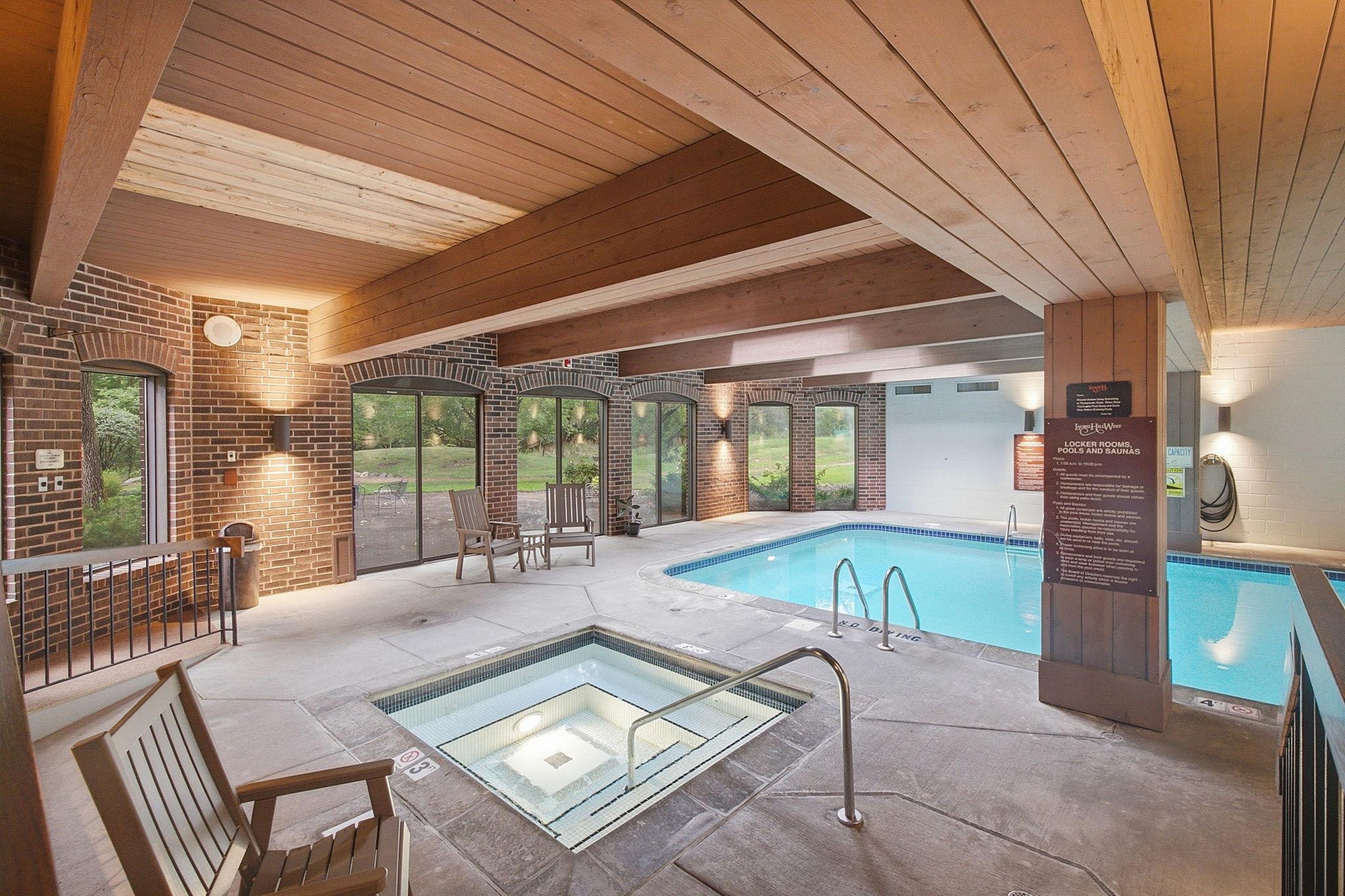 Indoor Pool & Spa - Indoor pool and spa area surrounded by large windows with views of the landscaped outdoor grounds.