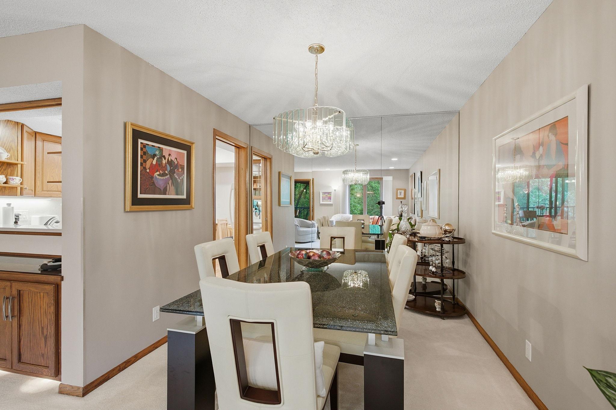 Dining Room - Generous dining area with mirrored accent wall and statement lighting, conveniently positioned between the kitchen and living room.