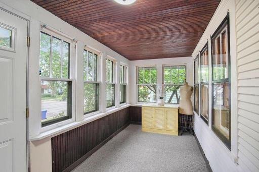 Enclosed front porch filled with natural light and surrounded by windows, a welcoming spot to enjoy your morning coffee.