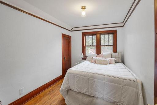 Upper-level bedroom 2 with hardwood floors, original wood trim, and double windows.
