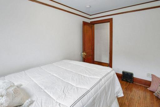 Another view of bedroom 2 highlights the original wood door, trim, and hardwood flooring.