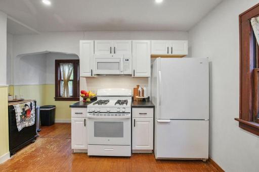 Another view of the kitchen, featuring white cabinetry, gas range, and charming original woodwork.
