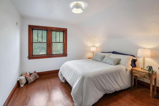Spacious upper-level bedroom 3 with hardwood floors, double windows, and charming sloped ceilings.