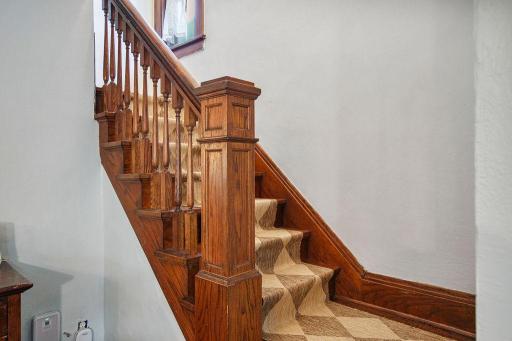 Original staircase showcases beautiful natural woodwork, detailed spindles, and a substantial newel post.