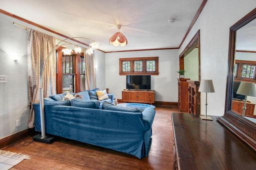Living room features large windows, warm hardwood floors, and original wood trim that adds timeless charm.