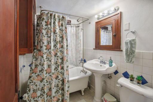 Full upper-level bath features a classic clawfoot tub, pedestal sink, and vintage-inspired tile.