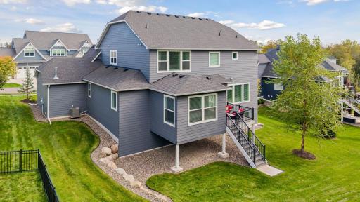 Rear exterior showcases the home's expansive design, deck, and beautifully maintained lawn.