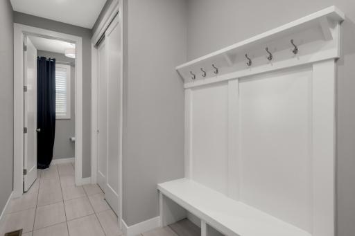 Functional mudroom features a built-in bench, hooks, storage, and convenient access to the main-level bath.