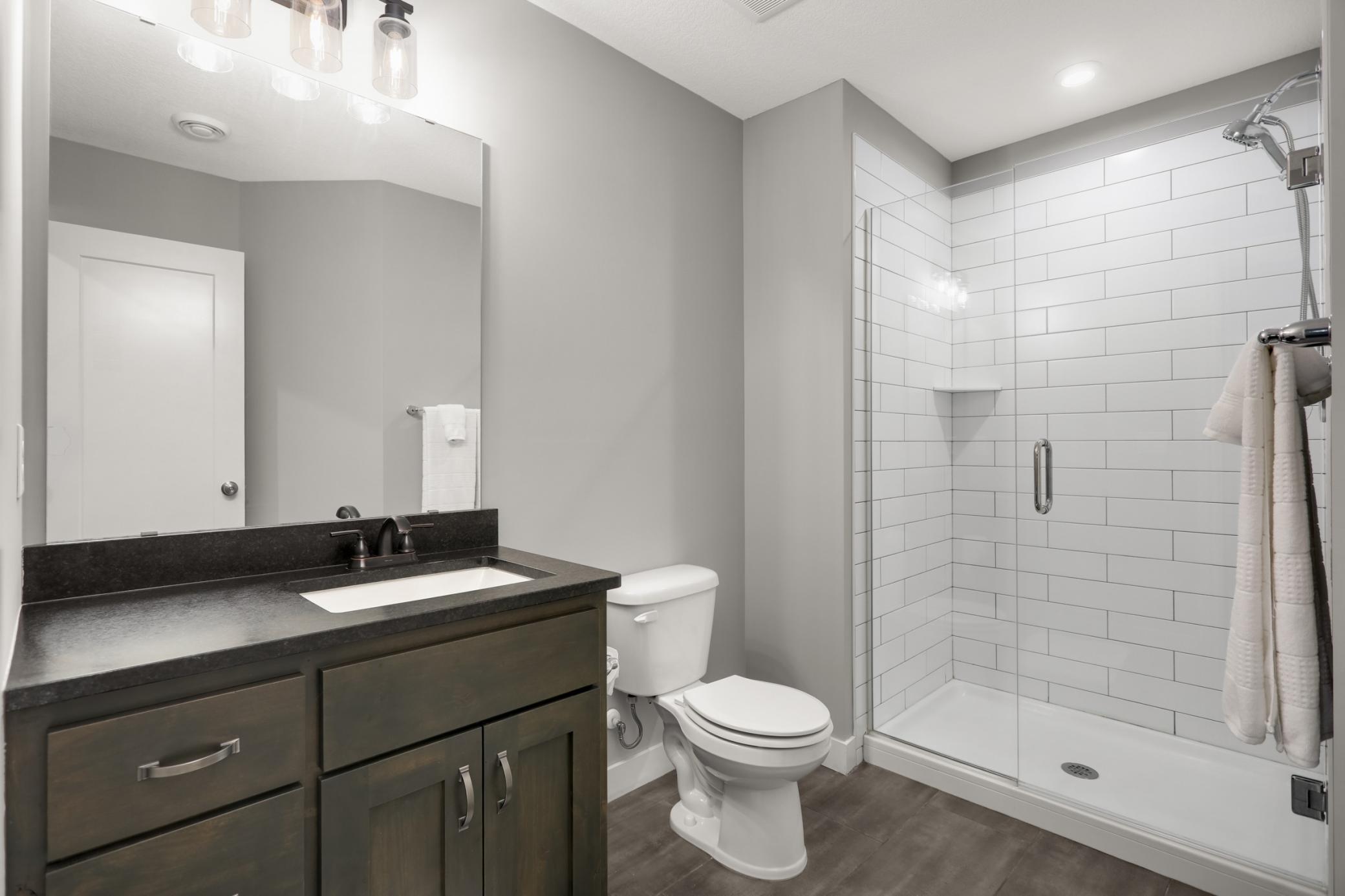 Lower-level bathroom offers a large tiled shower, updated vanity, and modern finishes.