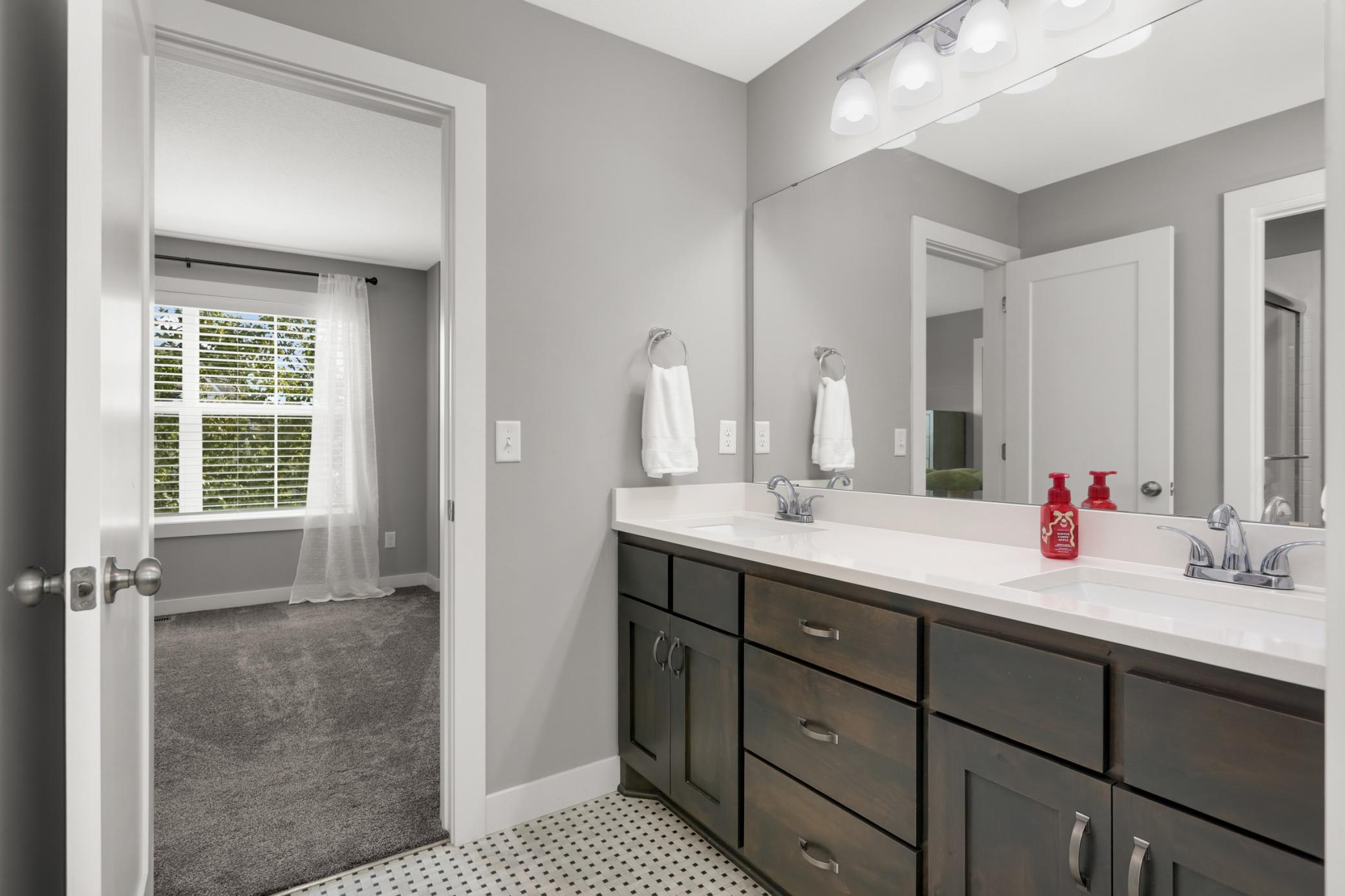 Jack-and-Jill-style bathroom features a long dual-sink vanity and excellent storage.