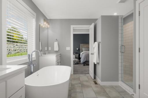 Primary bathroom features a freestanding soaking tub, glass-enclosed shower, dual vanities, and excellent natural light.