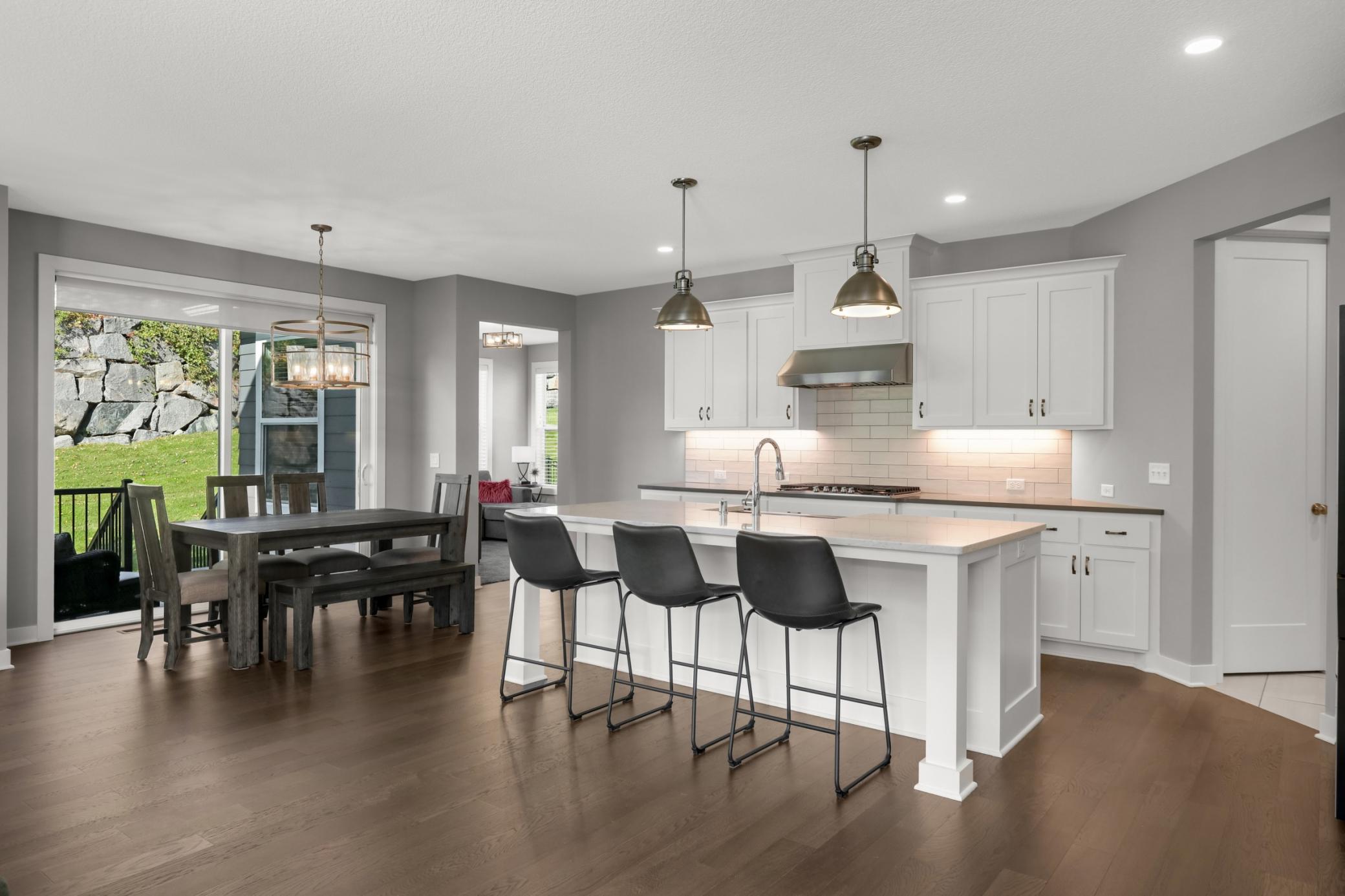 Crisp white cabinetry, stainless steel appliances, tile backsplash, and island seating create a polished kitchen.