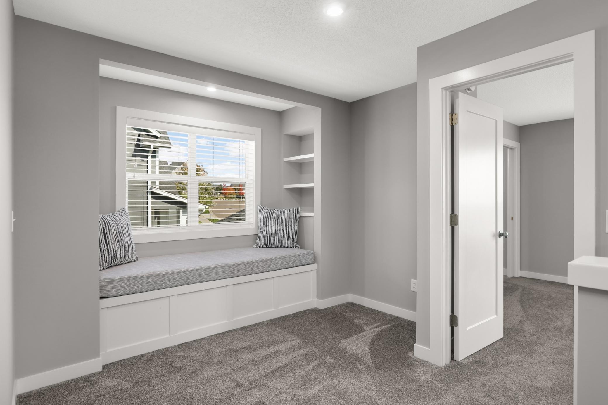 Charming built-in window seat creates a cozy reading nook with additional storage and shelving.