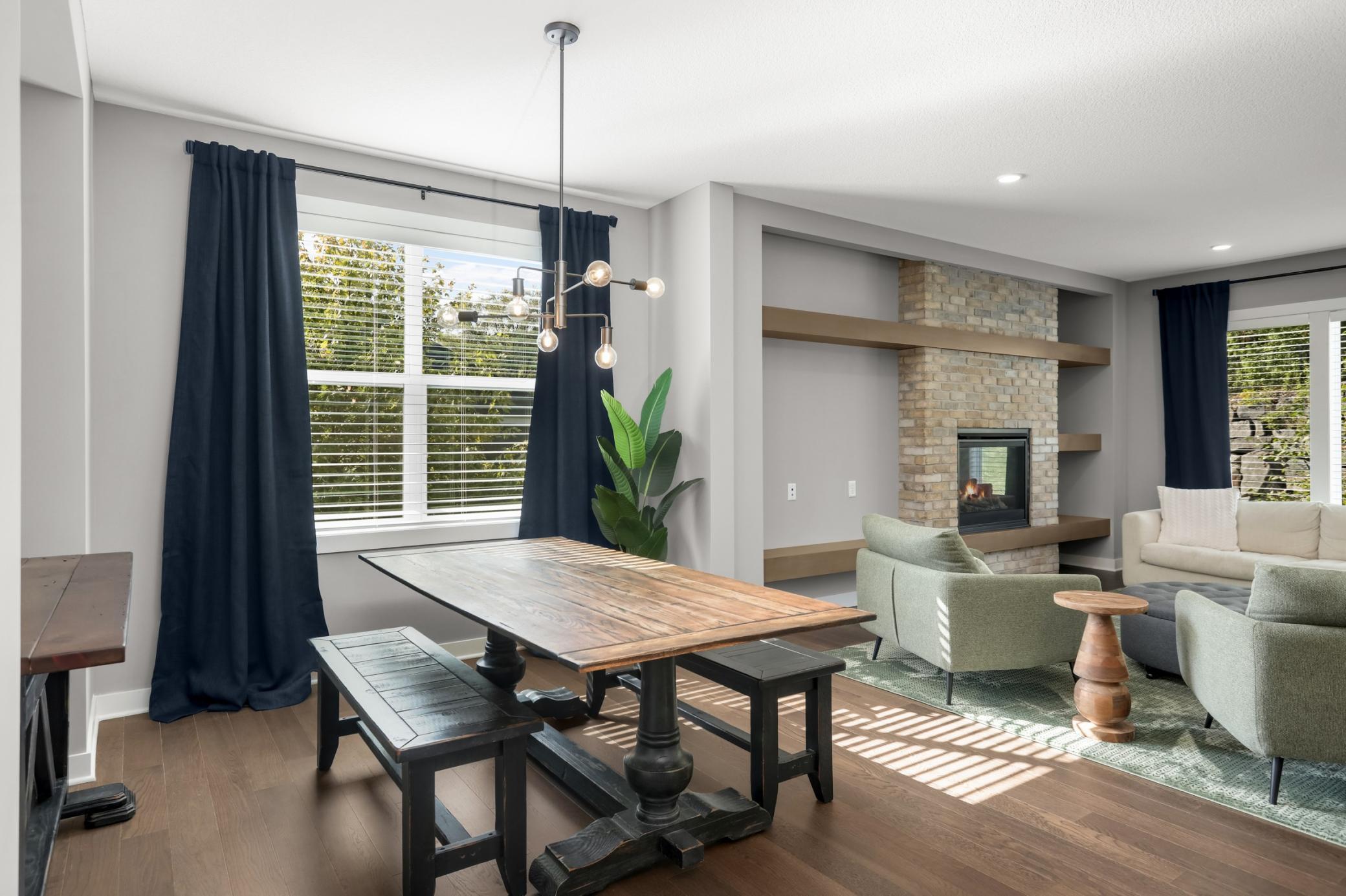Sun-filled dining area with hardwood flooring, oversized window, and contemporary lighting.