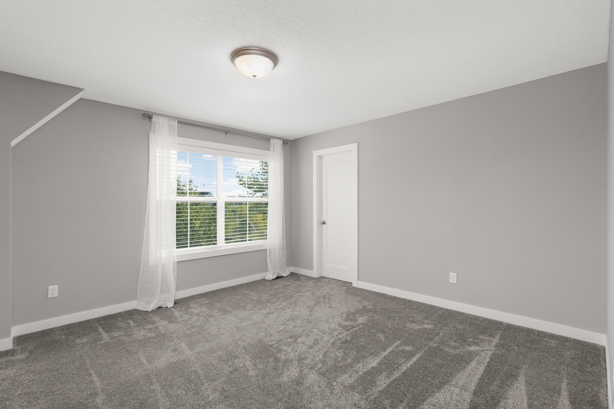 Spacious upper-level bedroom with a large window, fresh neutral finishes, and generous closet space.