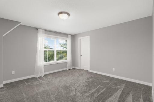Spacious upper-level bedroom with a large window, fresh neutral finishes, and generous closet space.