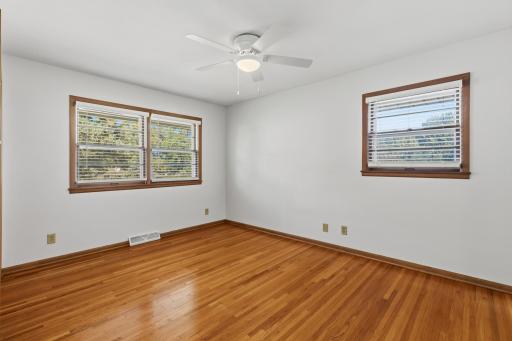 Bedroom #1 with ceiling fan/light and has windows on both sides of the wall.