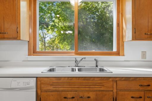 A closer look of the kitchen sink with window that overlooks a part of the backyard.