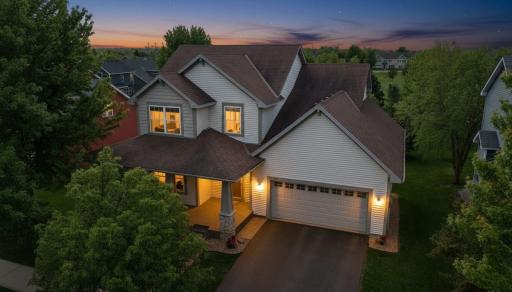 Evening charm shines at this beautifully landscaped home, featuring a welcoming wraparound front porch and inviting Towne Lakes neighborhood setting.