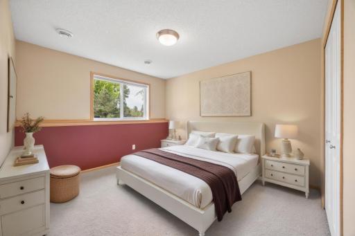 Perfect for guests, this lower-level 4th bedroom offers a comfortable retreat with great closet space and convenient access to a full bathroom—providing privacy and flexibility for overnight visitors, family, or a home office (Shown virtually staged)