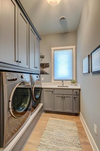 Thoughtfully designed laundry room features a convenient sink and plenty of storage to keep everyday essentials organized and within easy reach!