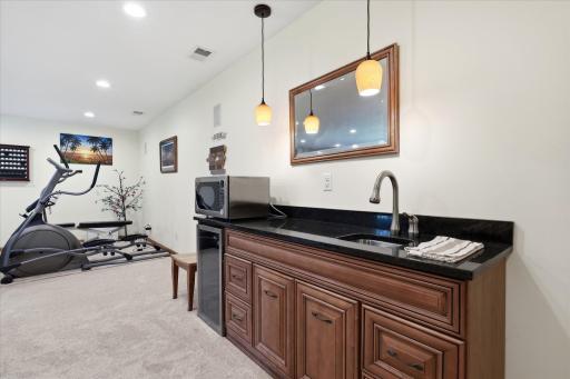Built-in wet bar w/pendant lites + granite counter top, undermount sink, small refrigerator (microwave stays),