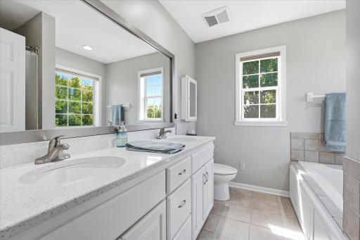 En-Suite Primary Bathroom On-Suite features: dual sink vanity w/white quartz ctr top + heated tile floors, jetted tub w/tile surround, separate shower and two windows