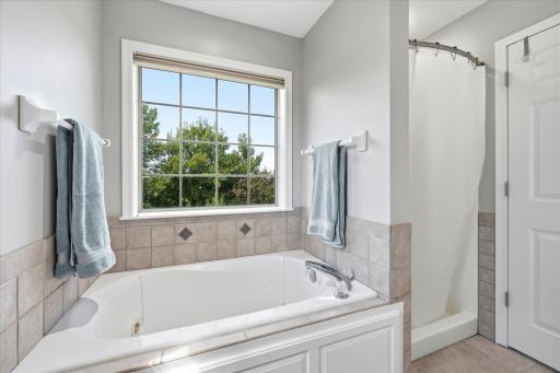 En-Suite Primary Bathroom On-Suite features: dual sink vanity w/white quartz ctr top + heated tile floors, jetted tub w/tile surround, separate shower and two windows