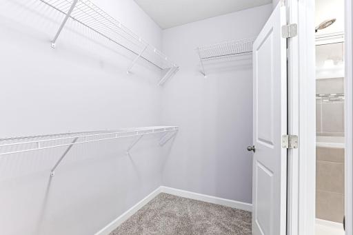 Well-organized walk-in closet offering generous hanging space, built-in shelving, and a clean, streamlined layout.