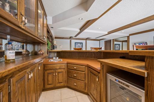 The family room bar area offers additional built-in cabinetry, a raised seating area, work sink and wine fridge. The glassed feature cabinetry is lighted.