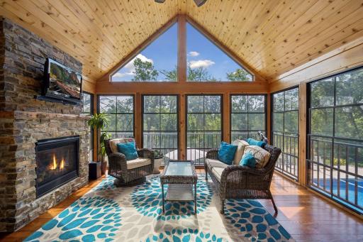 The vaulted sunroom has a cozy gas fireplace and commanding views of the pool, Rum River and side yard area.