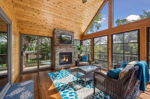 The delightful sunroom has vaulted wood ceilings, walls of windows, a cozy gas fireplace and sliding doors that open to the stairs to the side yard and pool deck, as well as sliders to the main level deck overlooking the pool area.
