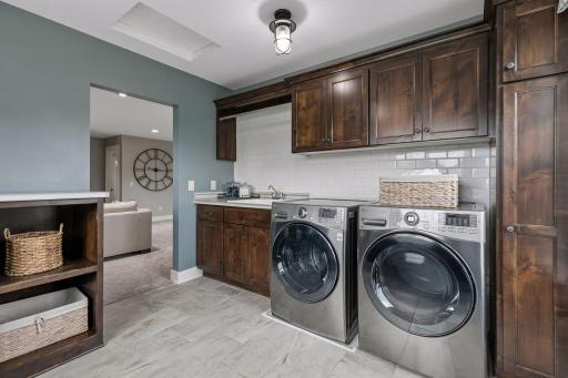 Laundry just got fun! Enjoy this oversized, functional laundry room complete with utility sink, tile backsplash, & an abundance of cabinets & cubbies.