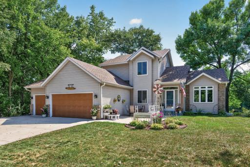 Spacious two-story surrounded by mature trees with a three-car garage and concrete driveway.