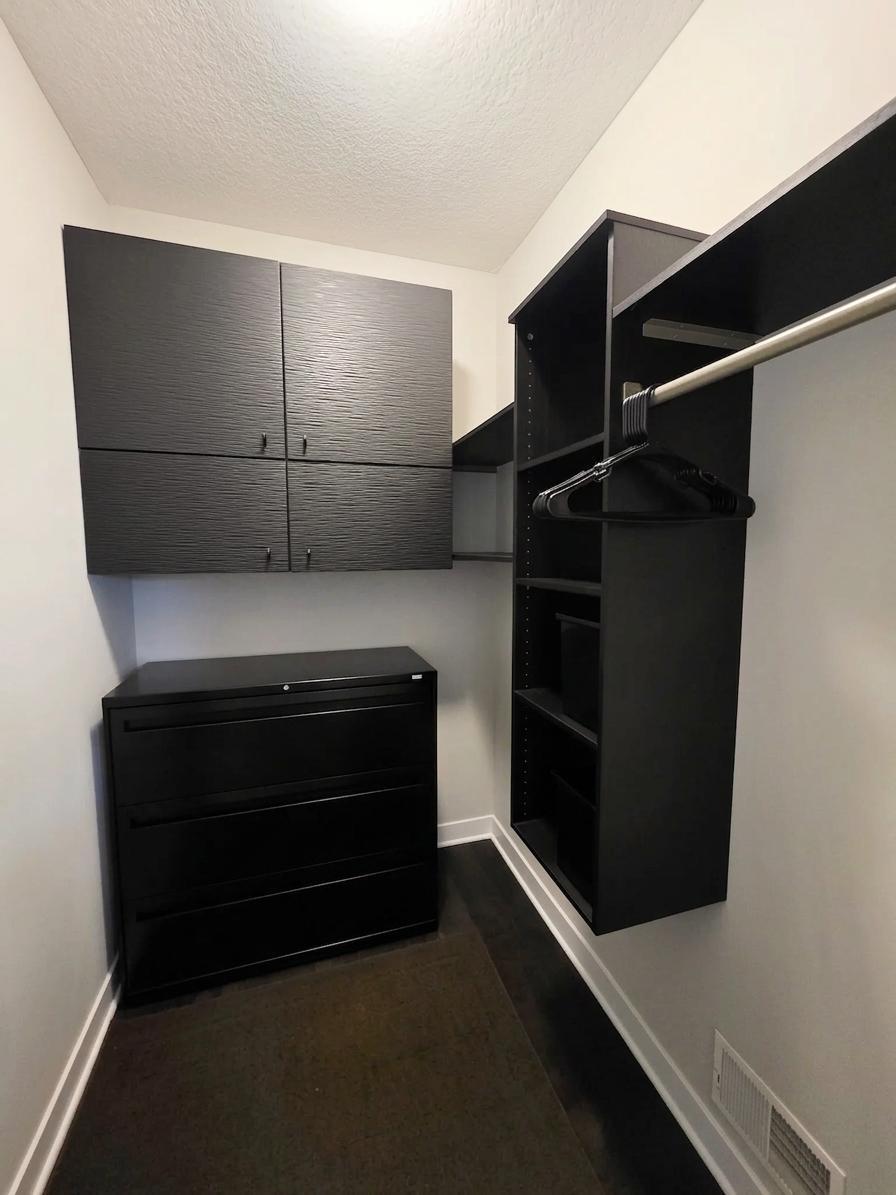 Walk-in storage area with built-in cabinetry, shelving and hanging space.