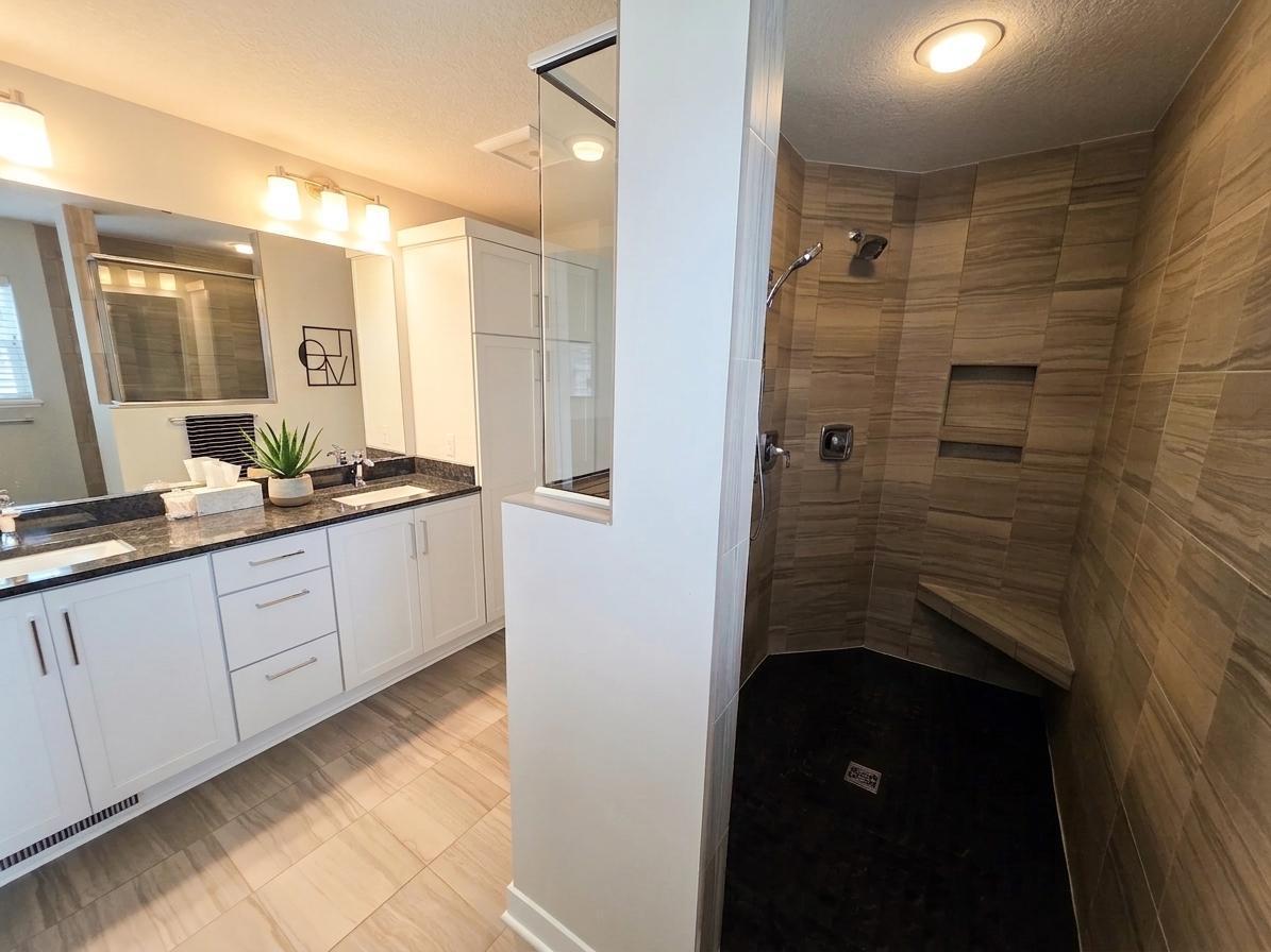 Private primary 3/4 bath featuring dual vanities and an oversized tiled walk-in shower with two shower heads.