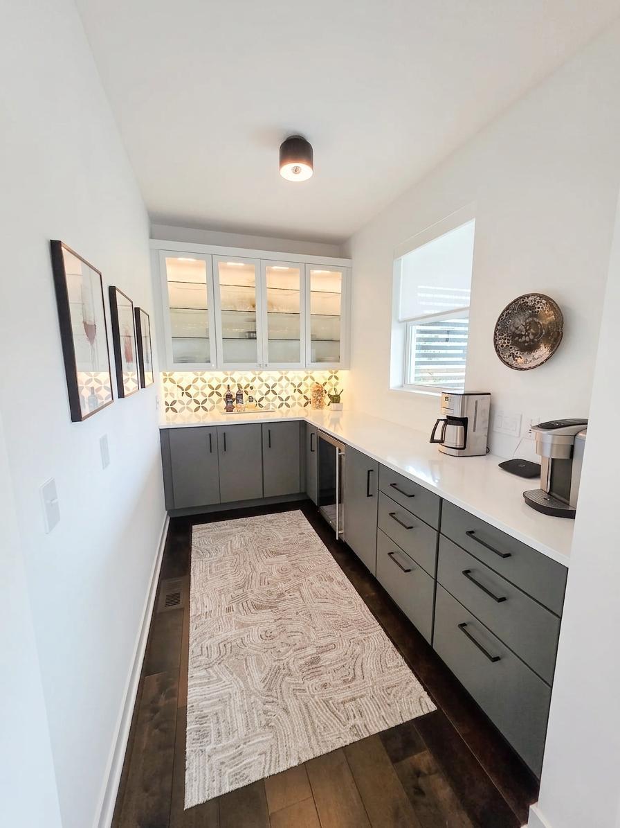 Large butler’s pantry with extensive cabinetry, illuminated glass-front uppers, beverage refrigerator and generous counter space.