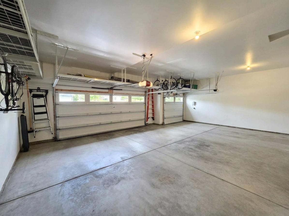 Rare four-stall attached garage is configured three-wide plus tandem, with extensive overhead and wall storage.
