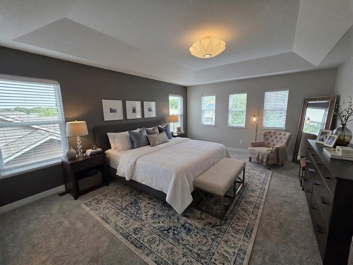 Expansive primary suite with tray ceiling, multiple windows and ample room for a sitting area.
