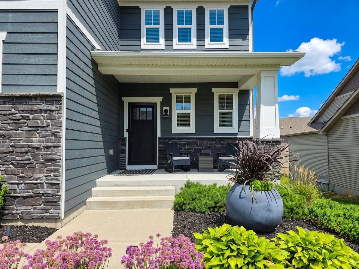 Concrete front porch and layered landscaping create a polished, welcoming entrance.