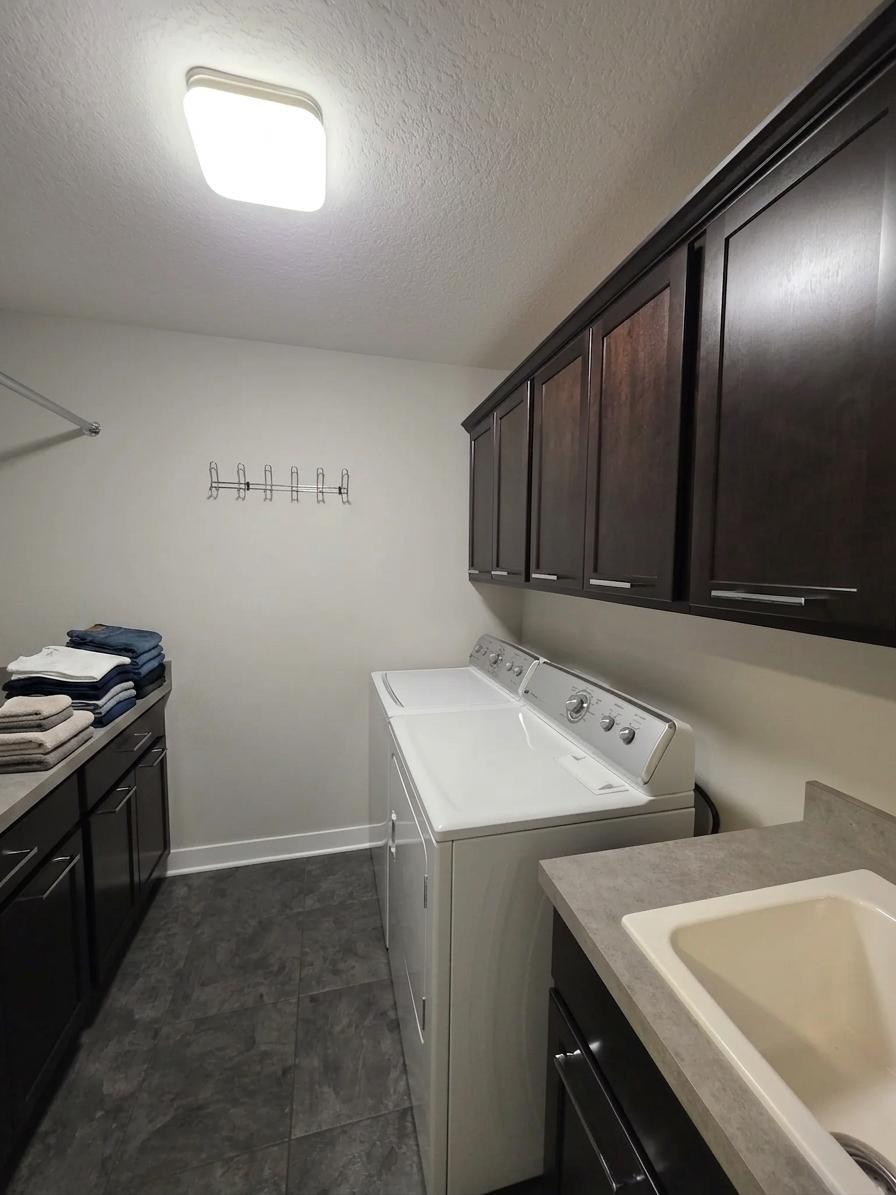 Convenient upper-level laundry room offers extensive cabinetry, counter space and utility sink.