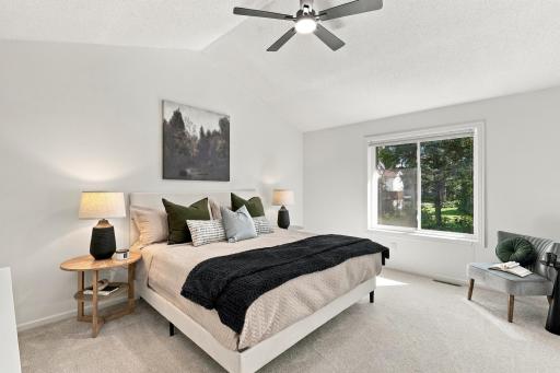 Primary bedroom on upper level with vaulted ceiling and big windows